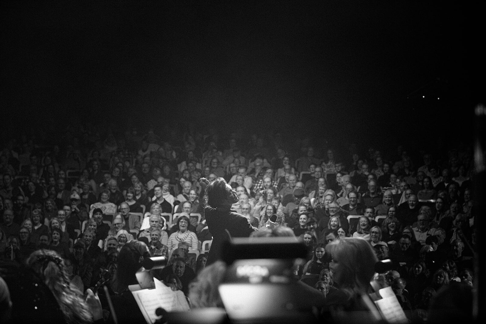 Black-and-white view of a conductor facing the audience at Boise Phil’s Music of Queen concert.