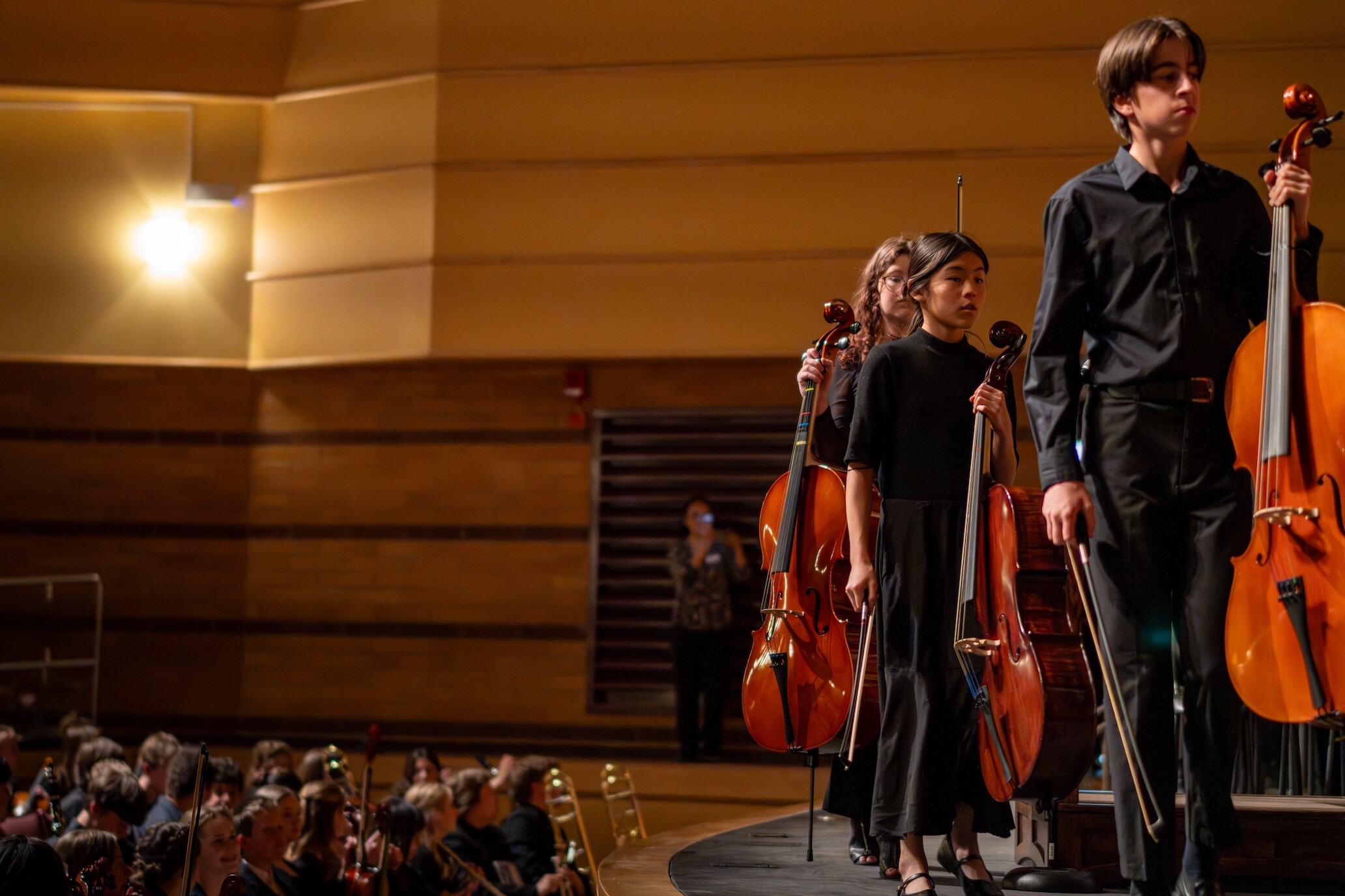 Boise Phil Youth Orchestra cellists stand with their instruments.