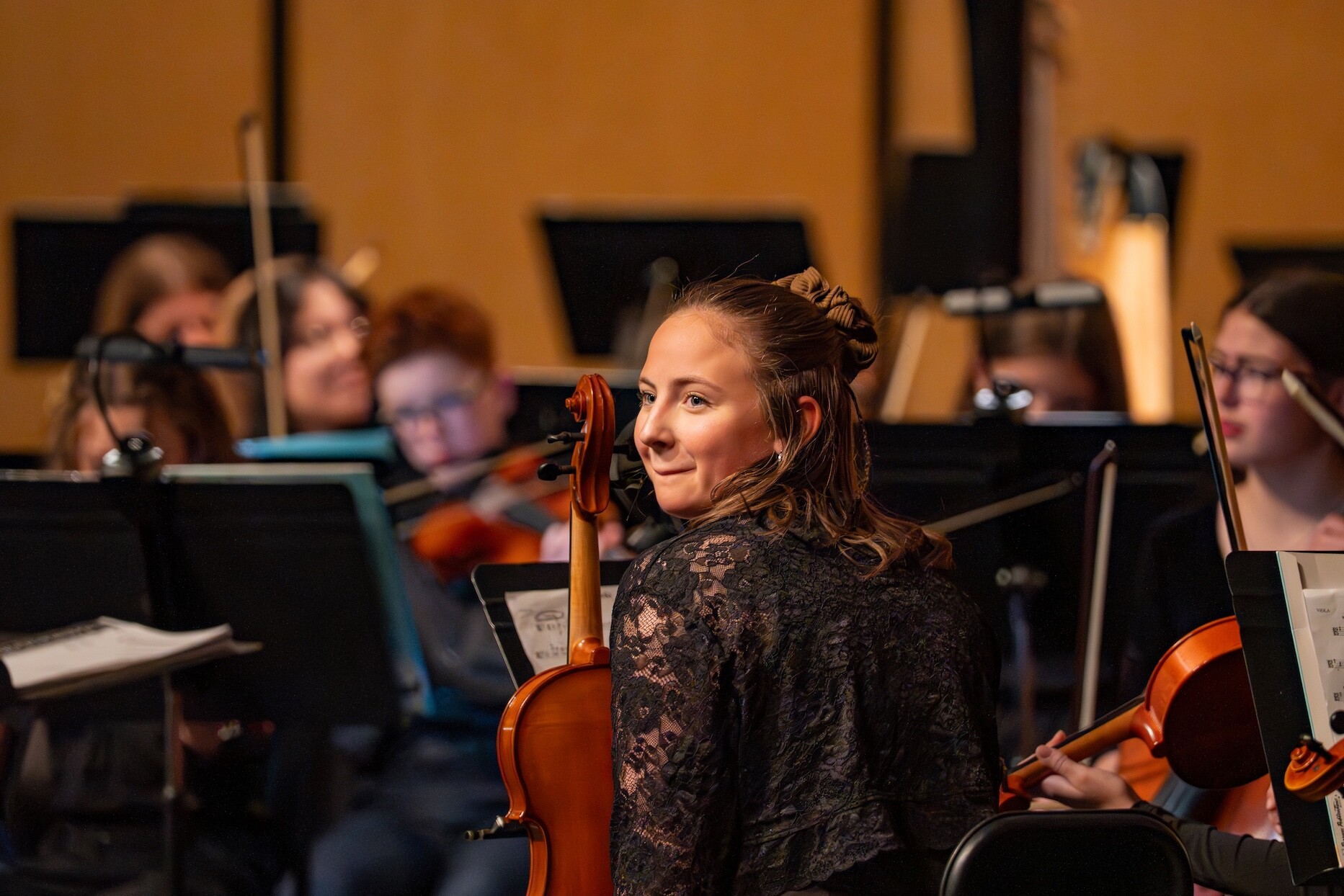 A smiling Boise Phil Youth Orchestra violinist holds a violin.