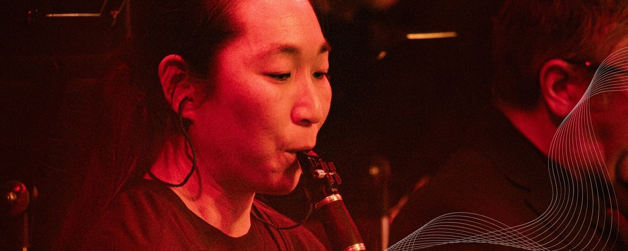 A Boise Phil clarinetist performs under red stage lighting.