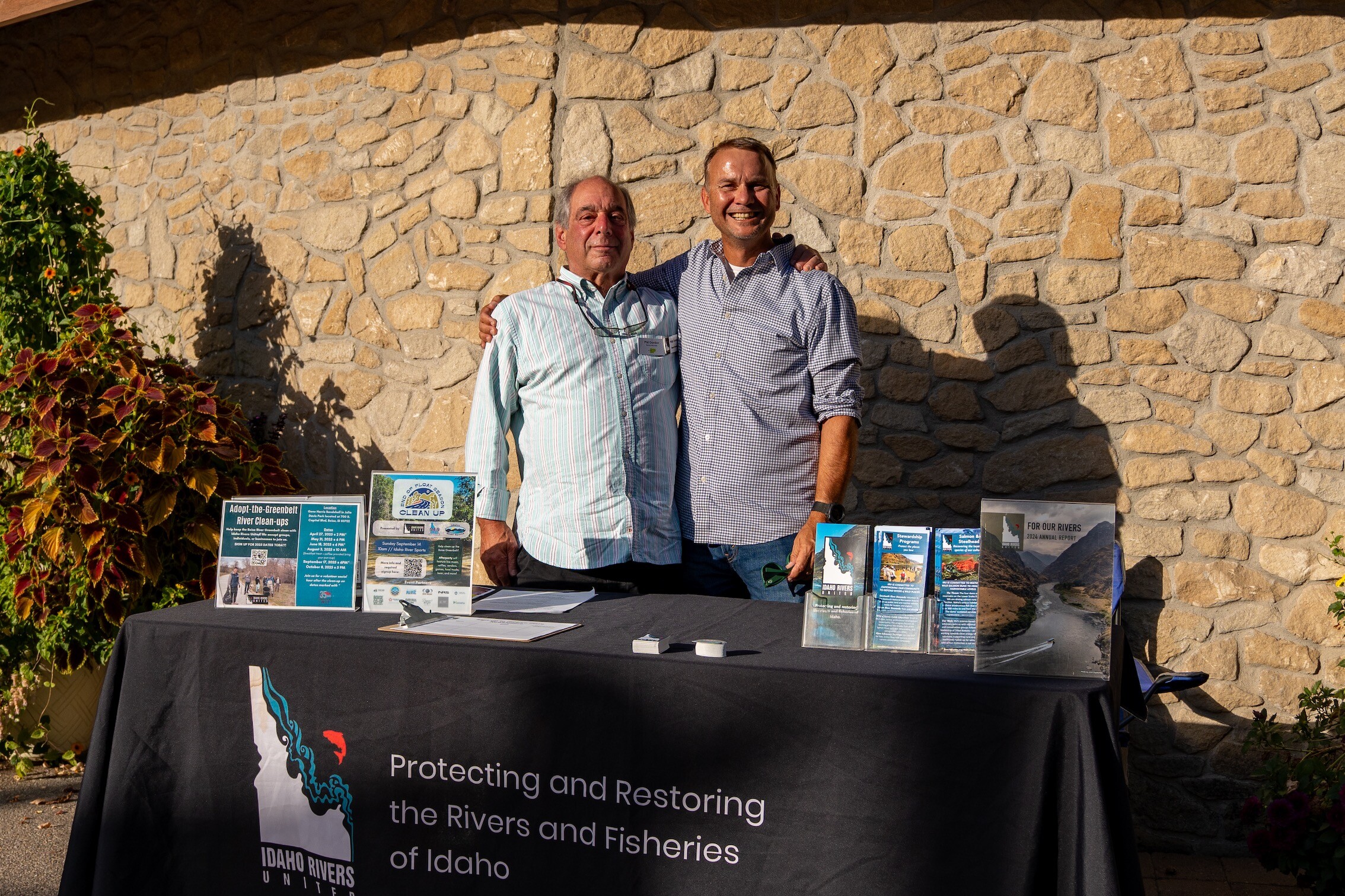 Two men greet visitors at an Idaho River United information table.