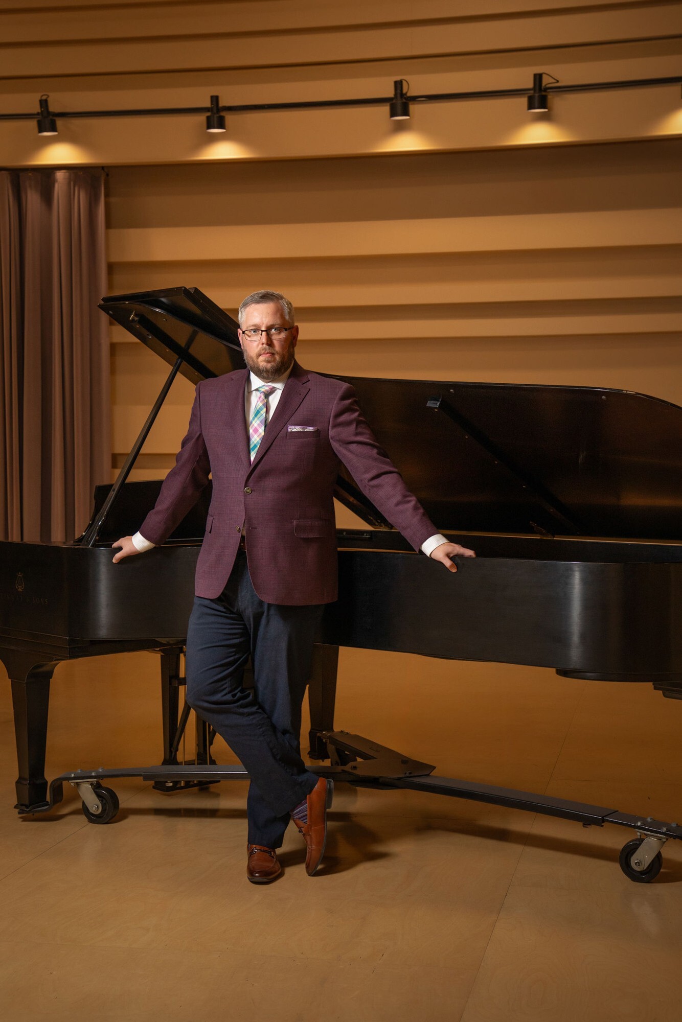 Brandon VanWaeyenberghe standing beside a grand piano